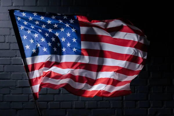 Dynamic waving usa flag in front of black brick wall, Independence Day concept — Stock Photo