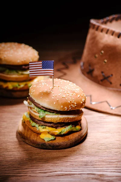 Tasty burgers on wooden table with american cowboy hat — Stock Photo