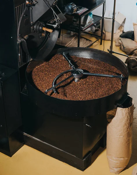 Tostador de café industrial con grandes bolsas de papel llenas de granos de café - foto de stock