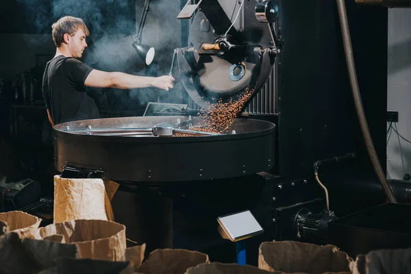 Чоловік контролює процес обсмажування кавових зерен в традиційній машині — стокове фото