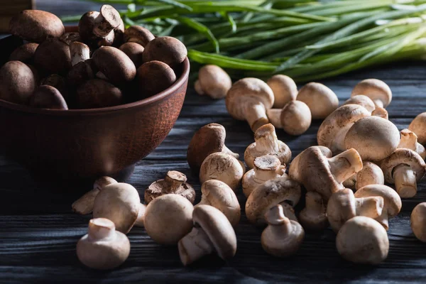 Close-up shot of raw champignon mushrooms with onion on dark wooden table — Stock Photo