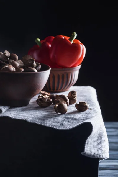 Rohe Champignon-Pilze mit Paprika in Schalen auf blauer Serviette auf schwarz — Stockfoto