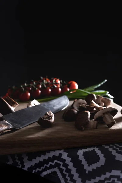 Close-up shot of champignon mushrooms with knife on wooden cutting board on black — Stock Photo