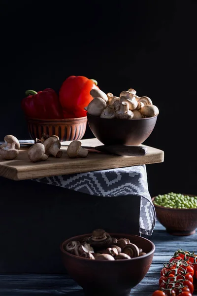 Champignon mushrooms and different vegetables on table on black — Stock Photo