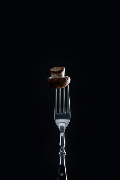 Raw champignon mushroom on fork isolated on black — Stock Photo