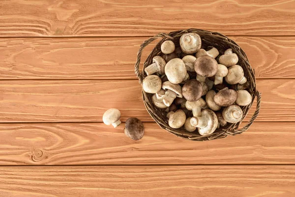 Top view of raw champignon mushrooms in basket on wooden surface — Stock Photo