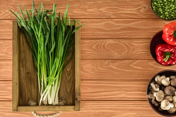 Top view of leeks in box and various vegetables on wooden tabletop — Stock Photo