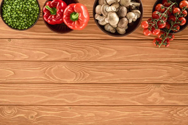 Vue de dessus des champignons champignon et divers légumes dans des bols sur table en bois — Photo de stock