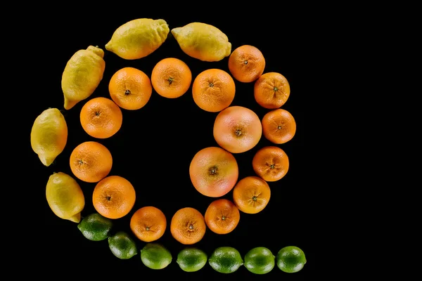 Top view of various fresh citrus fruits composition in spiral shape isolated on black — Stock Photo