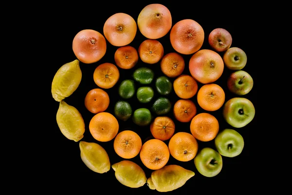 Vista superior de varios cítricos maduros composición en forma de espiral aislado en negro - foto de stock