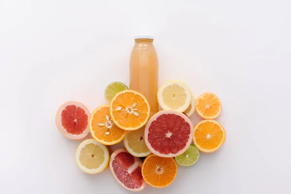 Vista superior de garrafa de suco com fatias de frutas cítricas na superfície branca — Fotografia de Stock