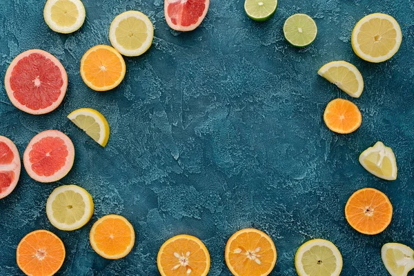 Vista superior de frutas cítricas cortadas em forma redonda na superfície de concreto azul — Fotografia de Stock