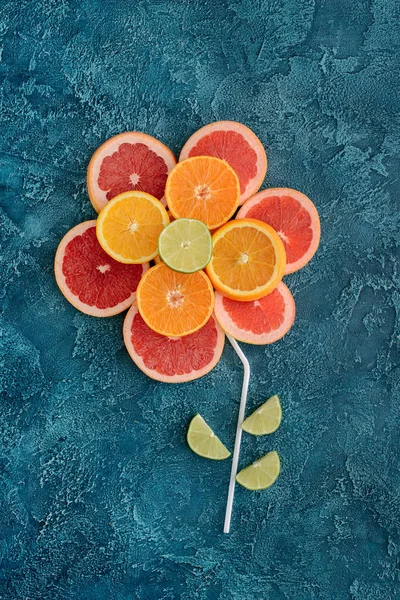 Vista superior da flor composta com fatias de frutas cítricas na superfície de concreto azul — Fotografia de Stock