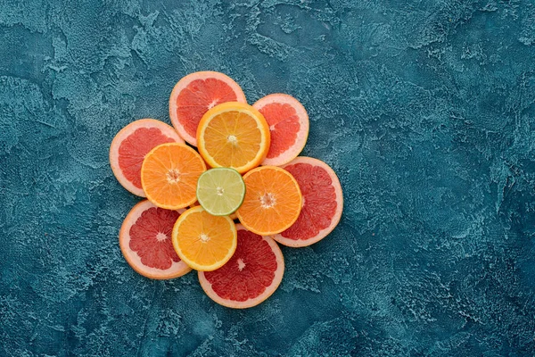 Top view of stacked various citrus fruits slices on blue concrete surface — Stock Photo