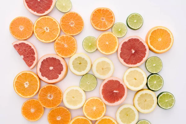 Top view of various citrus fruits slices spilled on white surface — Stock Photo