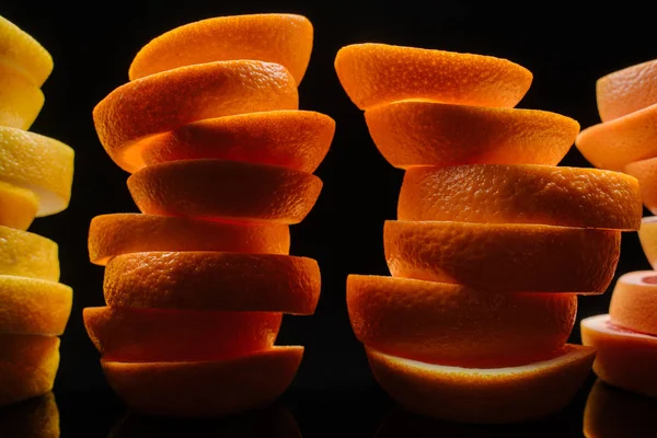 Nahaufnahme von gestapelten Scheiben verschiedener reifer Zitrusfrüchte-Scheiben isoliert auf schwarz — Stockfoto