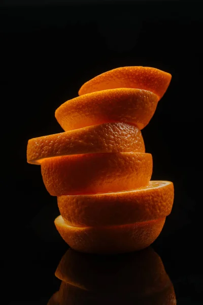Primer plano de rodajas apiladas de naranja madura aisladas en negro - foto de stock