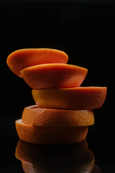 Primer plano de rodajas apiladas de pomelo aisladas en negro - foto de stock