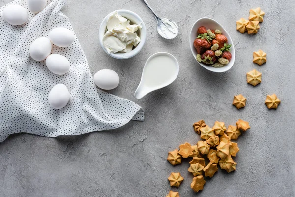 Flat lay with cut butter, sour cream and fresh strawberries ingredients for making pie on grey surface — Stock Photo