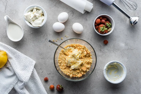 Vista superior da massa arranjada para torta, morangos, ovos crus de galinha e papel de assar em mesa cinza — Fotografia de Stock