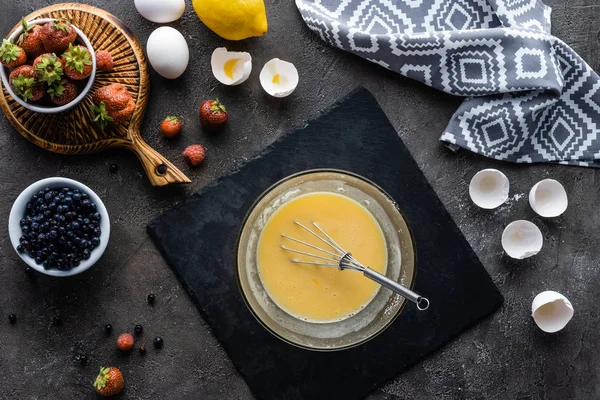 Vista dall'alto di fare la crema per il processo torta e gli ingredienti disposti sulla superficie grigio scuro — Foto stock