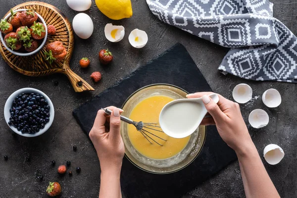 Abgeschnittene Aufnahme einer Frau, die Creme für hausgemachten Kuchen auf dunkelgrauer Tischplatte herstellt — Stockfoto