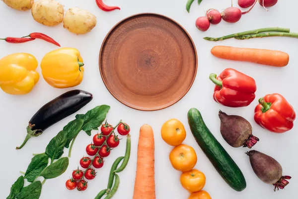 Vista superior de plato redondo vacío y verduras frescas maduras aisladas en blanco - foto de stock