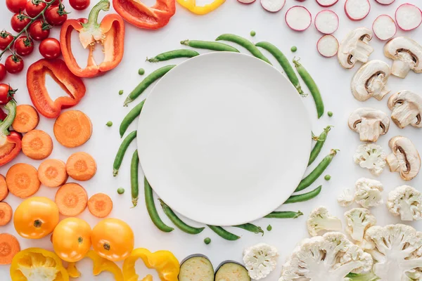 Vista superior de plato blanco redondo vacío y verduras orgánicas aisladas en blanco - foto de stock