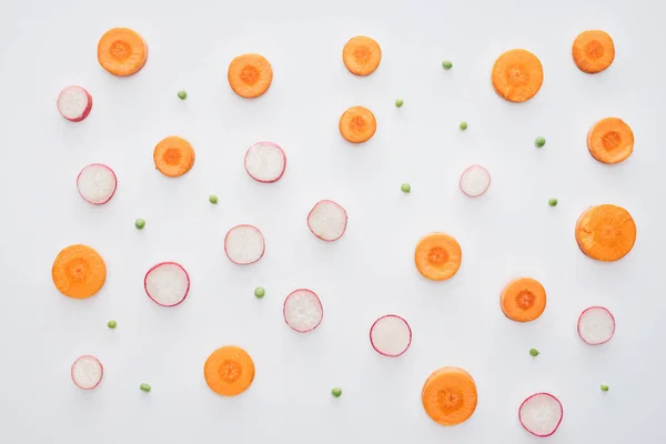 Vista superior de zanahoria fresca en rodajas, rábano y guisantes verdes aislados sobre fondo blanco - foto de stock