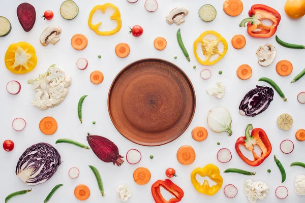 Вид зверху порожня кругла тарілка і свіжі нарізані органічні овочі ізольовані на білому — Stock Photo