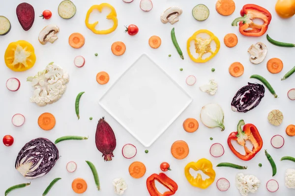 Vue du dessus de la plaque blanche vide et des légumes frais tranchés isolés sur blanc — Photo de stock