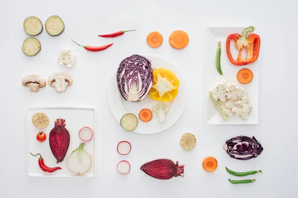 Vista superior de platos blancos y verduras frescas y sanas en rodajas aisladas en blanco - foto de stock