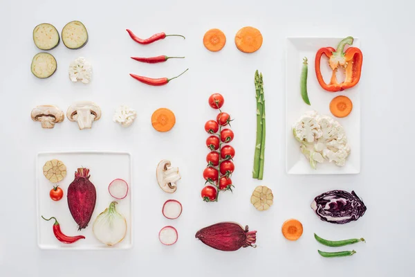 Vue de dessus des assiettes blanches et des légumes biologiques frais tranchés isolés sur blanc — Photo de stock