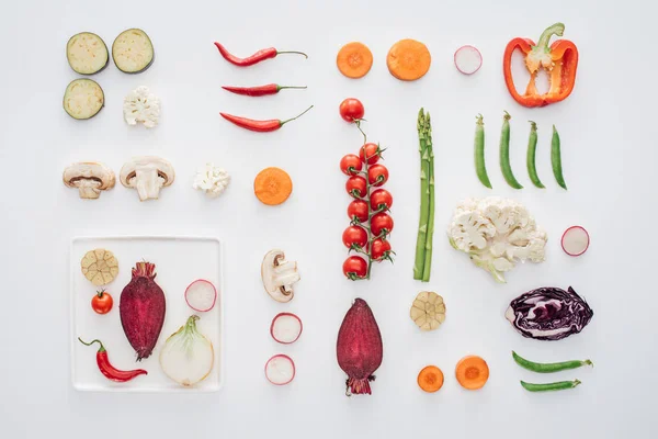 Вид зверху на білу тарілку і свіжі нарізані органічні овочі ізольовані на білому — стокове фото