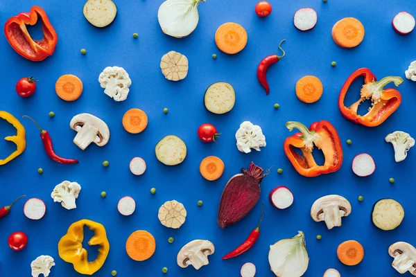 Vista superior de verduras frescas y sanas en rodajas sobre fondo azul - foto de stock