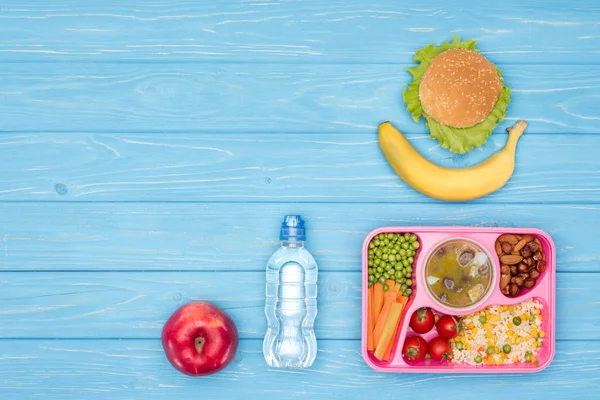 Draufsicht auf Tablett mit Mittagessen für die Schule, Flasche Wasser und Obst auf blauem Tisch — Stockfoto