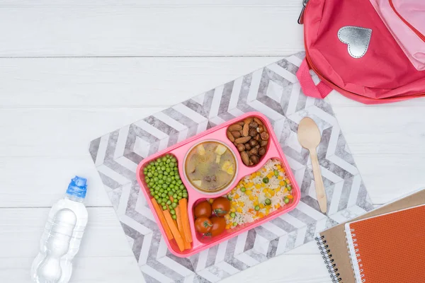 Top view of tray with kids lunch for school and copybooks on white tabletop — Stock Photo