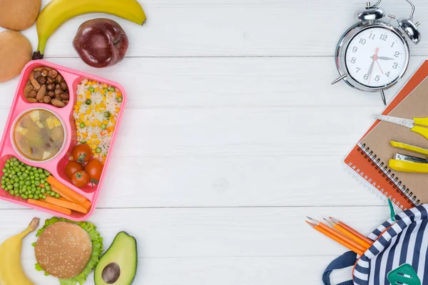 Vista dall'alto pranzo per bambini a scuola e sveglia con borsa sul tavolo in legno — Foto stock