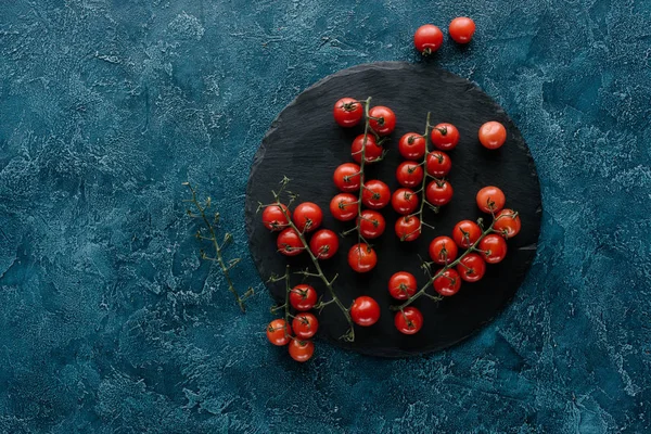 Tomates cerises mûres rouges sur panneau d'ardoise foncé — Photo de stock