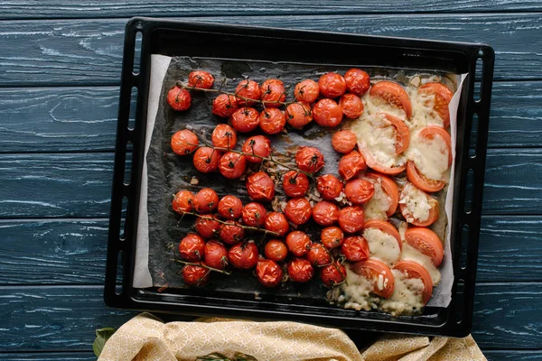 Baking pan with red cherry tomatoes with cheese on wooden table — Stock Photo