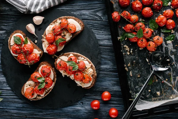Sandwichs au pain au fromage et tomates cuites au four sur une table en bois sombre — Photo de stock