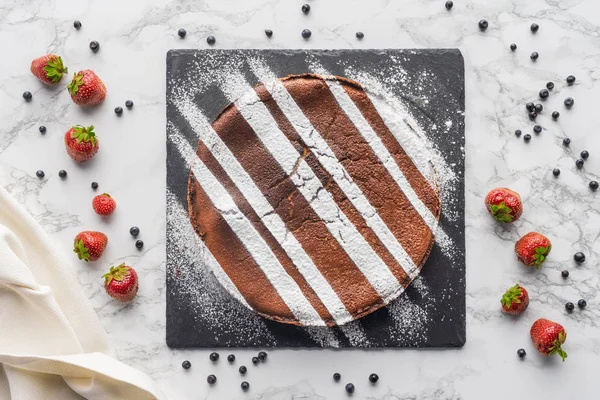 Vue de dessus de délicieux gâteau brun fait maison avec glaçage et baies fraîches sur la surface du marbre — Photo de stock