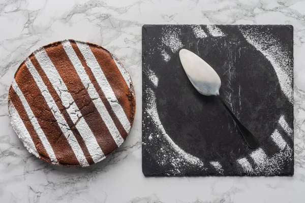 Vista superior de delicioso pastel casero y cuchara con glaseado en pizarra - foto de stock
