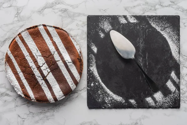 Vue de dessus de délicieux gâteau fait maison et cuillère avec glaçage sur ardoise — Photo de stock