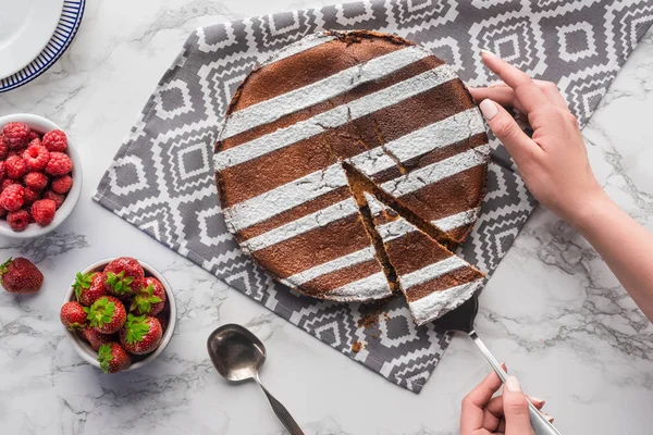 Vue de dessus des mains humaines et délicieux gâteau fait maison avec des baies fraîches sur la surface du marbre — Photo de stock