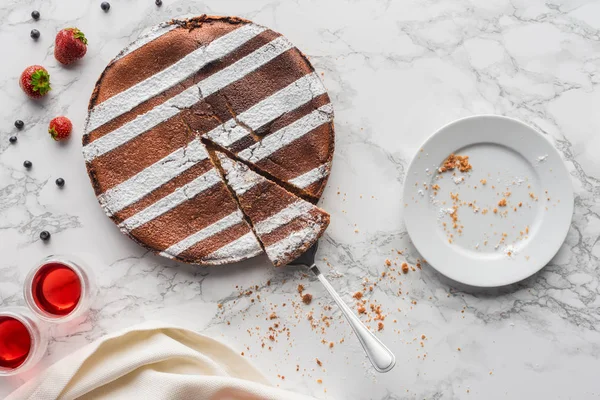 Blick von oben auf köstlichen hausgemachten Kuchen, frische Beeren und leeren Teller auf Marmoroberfläche — Stockfoto