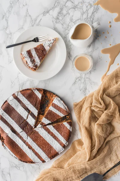 Top view of delicious homemade cake with icing and spilled hot cocoa on marble surface — Stock Photo