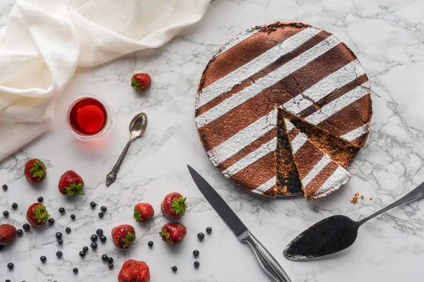 Blick von oben auf leckeren hausgemachten Kuchen, Sommergetränk und frische Beeren auf Marmoroberfläche — Stockfoto