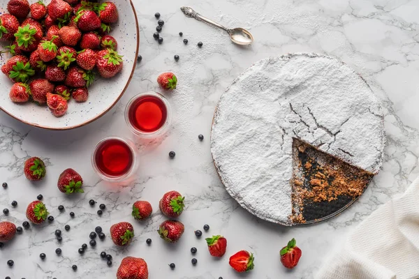 Blick von oben auf köstlichen hausgemachten Kuchen mit Zuckerguss und frischen Beeren auf Marmoroberfläche — Stockfoto