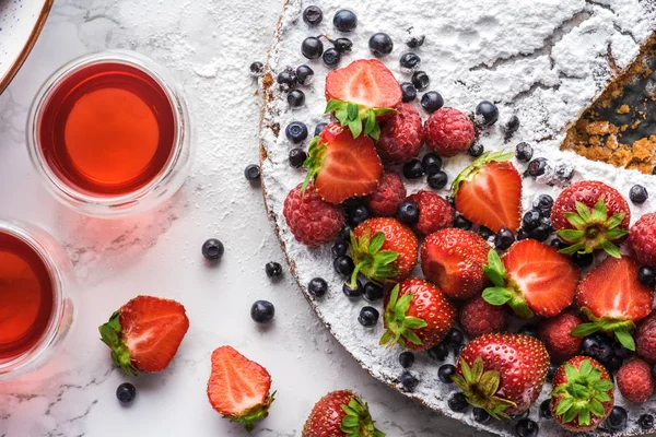 Top view of delicious homemade cake with berries and summer drink on marble surface — Stock Photo